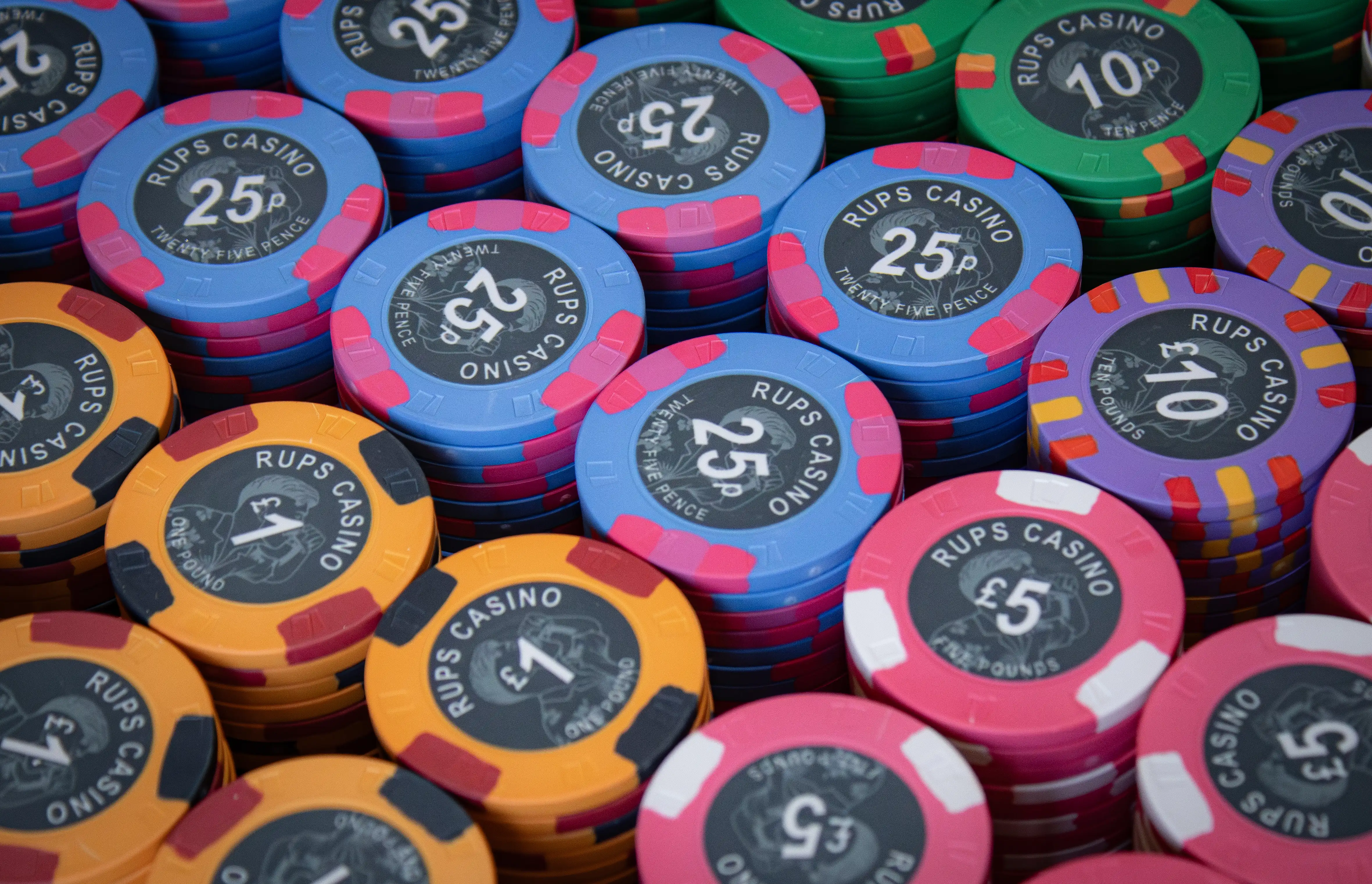 Close-up of a RUPS Casino custom ceramic poker chip showing direct-to-chip print detail on the photo-inspired background